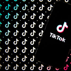 TikTokin logo puhelimen näytöllä. Taustalla näkyy logo ilman tekstiä.