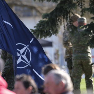 En Nato-flagga och två personer i militärklädsel i bakgrunden. Bilden är tagen i Lettland den 4 maj 2022.