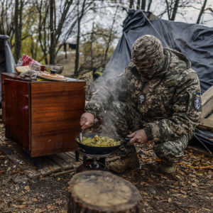 En ukrainsk soldat lagade mat utomhus i norra Cherson-regionen på söndagen. 