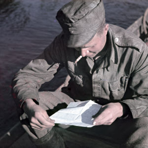 En soldat läser ett brev sittande i en båt.