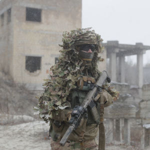 Ukrainalainen sotilas seisoo maastopuvussa raunioiden edessä Kiovan lähellä.