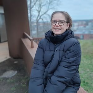 Markita Tiheäsalo tycker det är viktigt att träffas, fast man måste var försiktig och hålla avstånd. Markita Tiheäsalo, en dam med glasögon och mörkblå dunjacka, sitter vid en mur en dimmig novemberdag.