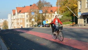 Mia Kukkola kommer susande på sin cykel. En kvinna cyklar på en röd cykelbana.
