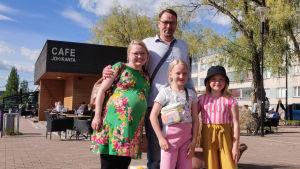 Marianne Winberg spenderade kvällen invid ån tillsammans med Sauli Honkanen, Liina Honkanen och Ella Stenström. Sommaren går i väntans tecken: i juli ska familjen få en till medlem. En gravid kvinna, en man och två flickor ler mot kameran. Bakom dem syns en uteservering invid ån.