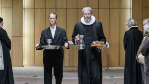 Svend (Joen Højerslev) och Johannes (Lars Mikkelsen) bär ut kyrksilvret då kyrkan stängs och säljs.. Karaktärerna Svend och Johannes omringade av folk.