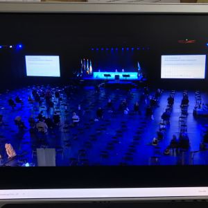 Tryggt men tomt i Samlingspartiets mötessal i Björneborg. De flesta följer från datorskärmen. Foto från datorskärm: Samlingspartiet samlas till partikongress i stor, tom sal i Björneborg.