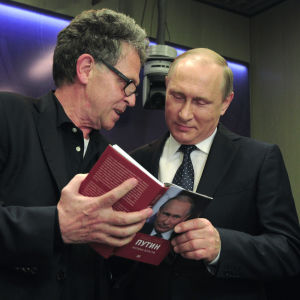 Hubert Seipel visar ett uppslag i sin bok Putin (med kyrilliska bokstäver på pärmen) för Vladimir Putin, som ser nöjd ut. De två männen står nära varandra.