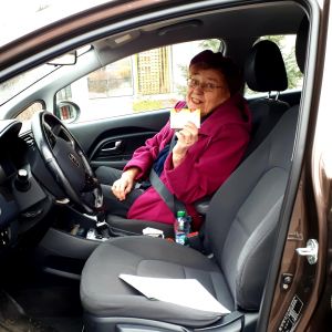 vanha nainen autossa näyttää karkkiaskia