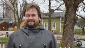 Andreas Lindén har forskat om tjädrar. En man med brunt hår och skägg står framför en minigolfplan iklädd en grå jacka.