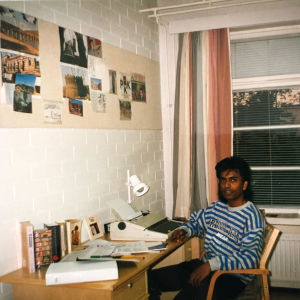 Nuori srilankalainen mies istuu kirjoituspöydän ääressä valkotiiliseinäisessä huoneessa.