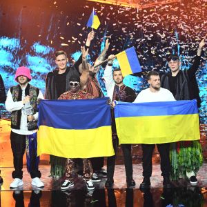 Personer som står på en scen med ukrainska flaggor i händerna.