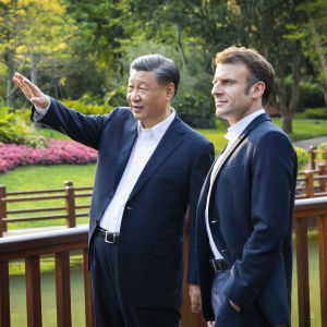 Xi Jinping och Emmanuel Macron står på en bro och tittar mot sidan. Xi pekar mot något.