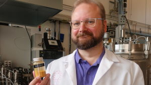 Hur skulle det smaka med proteinpulver till grönsakerna? Juha-Pekka Pitkänen iklädd labbrock visar upp en burk proteinpulver.