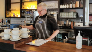 Mika Gehör är nöjd över att kunna öppna sin restaurang, men skulle önska ytterligare lättnader. En man står bakom en disk på en restaurang.