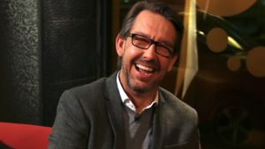Hasse Aro, känd från tv-programmet Efterlyst i Sverige. hasse aro sitter i en soffa