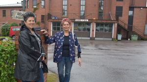 Lotta Lerviks (till vänster) har funderat på uttryckets ursprung. Karin Svahnström tror hon vet varifrån det kommer. Lotta Lerviks och Karin Svahnström står vid en grön häck. I bakgrunden syns en större byggnad av tegel.