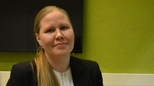 Professor Kati Miettunen. En kvinna med ljust hår tittar in i kameran. En grön vägg bakom.