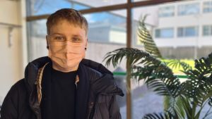 Kajsa Lassila har en flytt att se fram emot på valborg. En kvinna med munskydd tittar mot kameran. Bredvid till hennes vänster en grön växt.