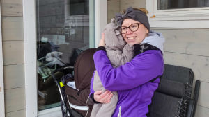 Nadina Vihinen och hennes man använder dotterns riktiga namn, för resten av världen är hon ännu Bönan. En kvinna i lila jacka ler och håller i en baby.