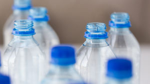Vatten på flaska innehåller mycket mikroplaster. Vattenflaskor i plast med blå skruvkork.