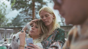 Det tar på att fylla år. Mitzi (Emmi Parviainen) i bästa vännen Veronikas (Laura Birn) famn. Födelsedagsbarnet Mitzi ligger i bästa väninnans famn på en altan.