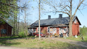 Byggnaden där dejorna och statarna bodde. ett gammalt stockhus i rödmylla. Framför huset en bil och gamla möbler (loppisgrejer)
