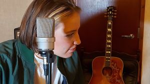 Att få arbeta med musik i studio är en uppfylld dröm för Ilon. Ilon, mikrofon och gitarri bakgrunden. Ansiktet i profil.