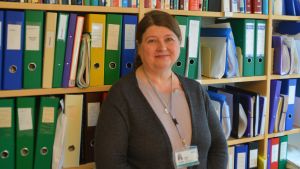 Överskötaren Tuula Silvola säger att personalen oroar sig. Kvinna framför en bokhylla.