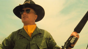 "Charlie don't surf!" så enkelt är det, tycker Kilgore (Robert Duvall). ("Charlie" är militärslang för fienden Viet Cong.) Bill Kilgore (Robert Ruvall) står med ett gevär i handen och ser nöjd ut.