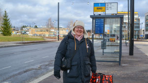 Marianne Bäckman tycker att det känns otryggt att åka utan säkerhetsbälte. En kvinna med en röd kasse i handen står vid en busstation i Nickby.