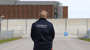 Både fångar och personal på Åbo fängelse har överlag tagit väl emot nya instruktioner och regler som kommit till följd av coronakrisen, säger Björn Lindström. En man i uniform står utanför porten till Åbo fängelse med ryggen vänd mot kameran..