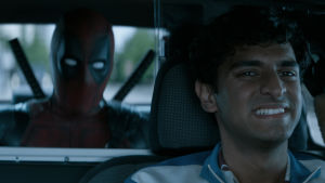 Taxichauffören Dopinder kör bil med Deadpool i baksätet.