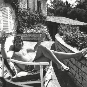 Svartvitt foto på Ozzy Osbourne i solstol med drink i trädgården