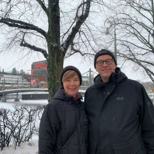 Raija och Timo står i svarta jackor vid Aura å i Åbo 