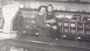 Hasse med en av butiksflickorna Svartvitt fotografi taget på 1950-talet i Gröna Boden i Bromarv, en liten matbutik