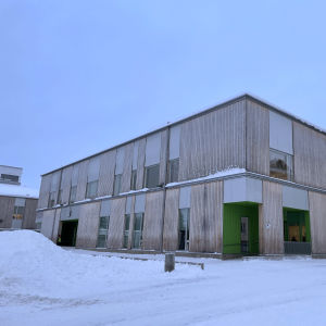 Puusta rakennettu koulu lumisessa maisemassa.