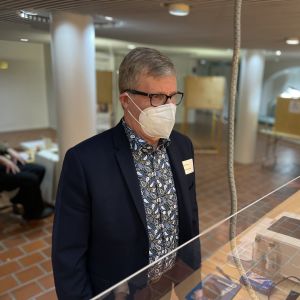 Mies seisoo kunnantalon aulassa maski kasvoillaan.