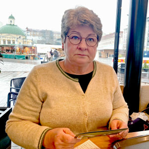 En kvinna i glasögon med postkort i handen. 