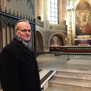 Arkkipiispa Tapio Luoma seisoo Turun tuomiokirkon alttarin lähellä ja katsoo kameraan.
