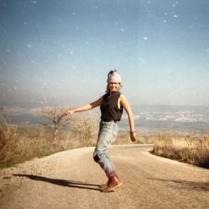 Pia Lindy tanssii tiellä, joka on korkean vuoren laella, taustalla Jordan Valley.