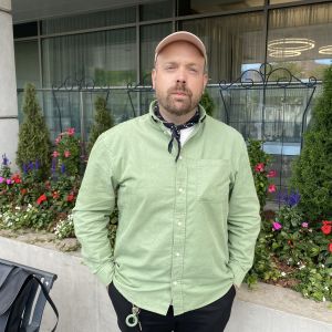 Man som står intill en blombänk.