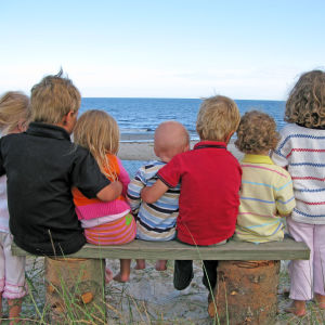 sju barn i olika ålder tittar ut över havet