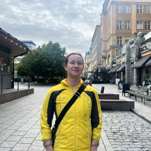 Kvinna i gul jacka ler mot kameran.