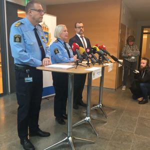 Tre personer står framför mikrofoner.