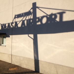 Skuggbild vid Vasa flygplats, i fotot ser man skuggan av flygplatsskylten mot terminalväggen.