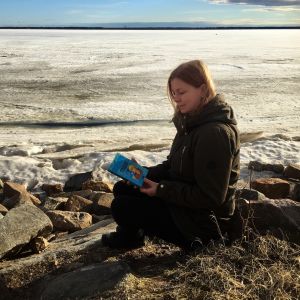 Hannan kirjokansi -blogin pitäjä lukee kirjaa Oritkarin talvisella rannalla.
