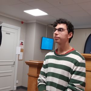 Emmanuel Jhutti ung mörkhårig man med svarta glasögon och grönvitrandig blus står i skolkorridor