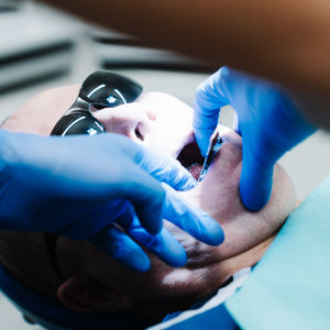Äldre man får tandvård i en tandklinik.