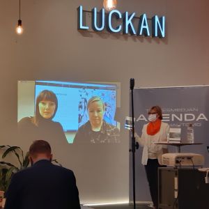 Ordförande i styrgruppen för Tankesmedjan Agenda Anna-Maja Henriksson (också justitieminister) höll öppningstal när rapporten lanseras. En kvinna i ansiktsskydd talar vid ett podium framför en skärm där två personer sins.