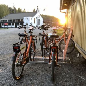 Fyra orange stadscyklar vid ett cykelställ.